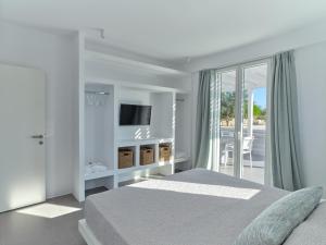 a white bedroom with a bed and a balcony at Blue Mare Villas in Naousa