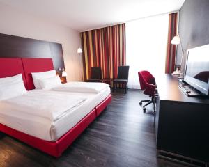 ein Hotelzimmer mit Bett, Schreibtisch und Fernseher in der Unterkunft PLAZA INN Wels in Wels