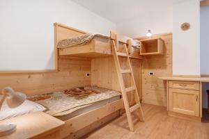 a bunk bed in a wooden room with a ladder at Appartamenti Boé 1 in Livinallongo del Col di Lana