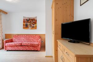 a living room with a couch and a flat screen tv at Appartamenti Boé 1 in Livinallongo del Col di Lana