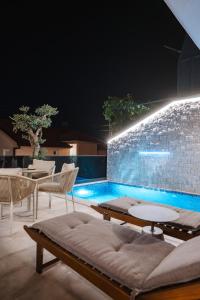 a swimming pool with chairs and a table and a couch at Villa The One Mostar with Heated Pool & Jacuzzi in Mostar