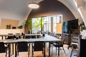 a dining room with tables and chairs and large windows at Hotel De Roode Schuur in Nijkerk