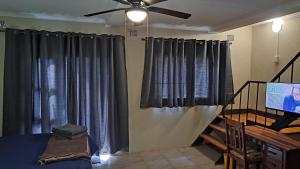 ein Wohnzimmer mit Deckenventilator und Vorhängen in der Unterkunft Declan House in Louis Trichardt