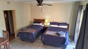 ein Schlafzimmer mit zwei Betten und einem Deckenventilator in der Unterkunft Declan House in Louis Trichardt + 11 Fotos