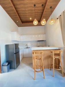 a kitchen with a counter and two chairs and a refrigerator at The Res Village Lombok in Kuta Lombok