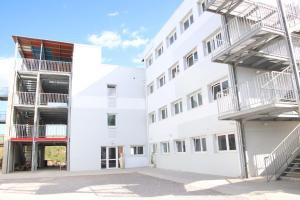 a white building with two balconies and a staircase at Campus Arkenciel - Montpellier Est in Mudaison