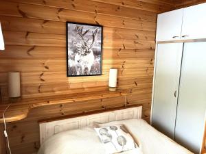 a bedroom with a wooden wall with a picture of a deer at Lumi-Ilves Iso-Syöte in Syöte