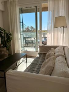 a white couch in a living room with a balcony at Depto cálido y moderno in San Nicolás de los Arroyos
