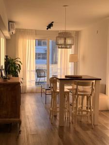 a dining room with a table and chairs and a room with a window at Depto cálido y moderno in San Nicolás de los Arroyos