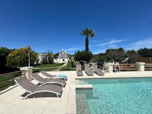 a group of lounge chairs next to a swimming pool at Trullo Suenn - piscina privata in San Michele Salentino