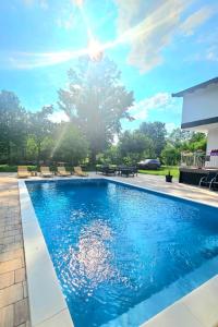 a pool with chairs and a tree in the background at Vikendica na Sani Datea in Sanski most