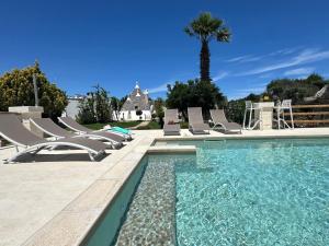 a swimming pool with lounge chairs and a palm tree at Trullo Suenn - piscina privata in San Michele Salentino