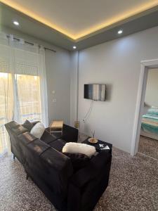 a black leather couch in a living room with a window at Cozy Central Home with Balcony in Alexandroupoli