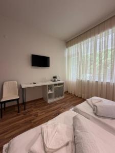 a room with two beds and a desk with a television at Hotel Captain in Gonio