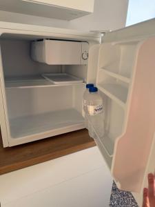 an open refrigerator with a bottle of water in it at Cozy Central Home with Balcony in Alexandroupoli