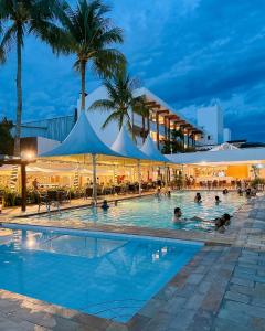 a swimming pool with people in a hotel at night at Ubatuba Palace Hotel in Ubatuba