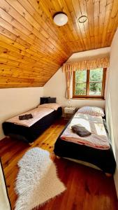 a bedroom with two beds and a wooden ceiling at Chalupa u rybníčku in Doksy +30 photos