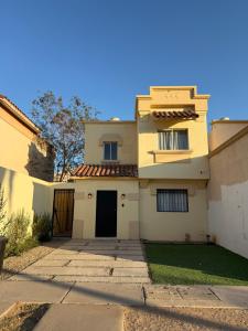 a white house with a gate and a building at Casa privada con estacionamiento in Hermosillo