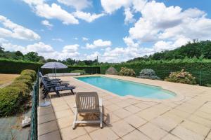 a swimming pool with two lawn chairs and an umbrella at Gite xl proche Grottes Lascaux in Fossemagne