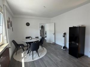 a living room with a table and chairs and a refrigerator at Ferienwohnung Auszeit in Vöhl +5 photos