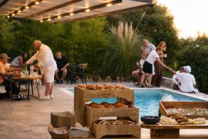 a group of people standing around a swimming pool with a party at Kefi Luxury Villas in Limenas +123 photos