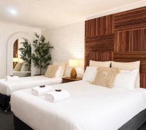 two beds in a room with two white beds at Beachmere Palms Motel in Beachmere