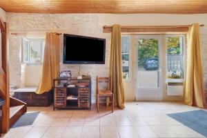 a living room with a flat screen tv and a desk at Gite xl proche Grottes Lascaux in Fossemagne