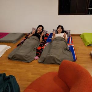 two girls are laying on a bean bag couch at No Plans No Complaints Backpackers Hostel in Ayer Itam