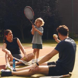 a group of people sitting on a tennis court with a child at Pokoje w Oberży Czarny Groń in Rzyki