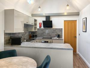 a kitchen with white cabinets and a counter with a table at The Barn - Uk50912 in Wansford
