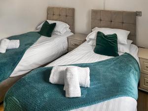 two beds with green and white towels on them at The Barn - Uk50912 in Wansford