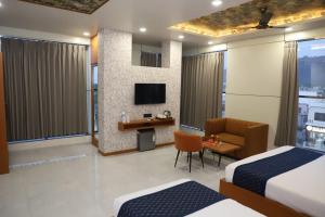 a hotel room with two beds and a desk and a tv at Hotel Pride Of Chittor in Chittaurgarh