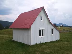 a white barn with a red roof in a field at Under Milky Way in Podgora