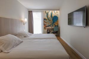 a hotel room with two beds and a flat screen tv at The Originals Boutique, Hôtel Cassitel, Cassis in Cassis