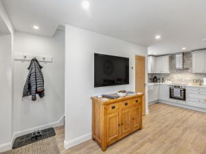 a kitchen with white cabinets and a tv on a wall at Fallow's Holt in Buildwas