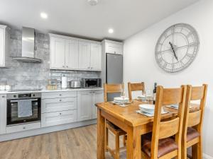 a kitchen with a table and chairs and a clock on the wall at Fallow's Holt in Buildwas