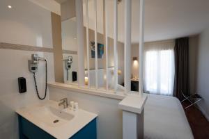 a bathroom with a sink and a bed with a mirror at The Originals Boutique, Hôtel Cassitel, Cassis in Cassis
