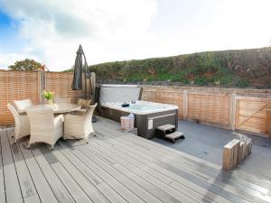 a deck with a hot tub and a table and chairs at Primrose-Uk34614 in Nether Stowey