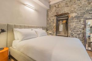 a white bed in a room with a stone wall at La Corte del Lario - Contrada Vecchia in Varenna +4 photos