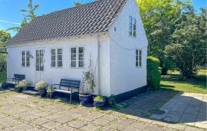 a small white house with a bench in a yard at Strandhytten in Allinge +11 photos