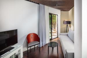 a living room with a couch and a tv at Monaco Suites Hotel in Lignano Sabbiadoro