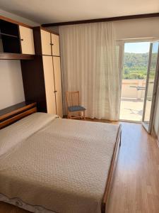 a bedroom with a bed and a sliding glass door at Apartmani Ankica in Kampor