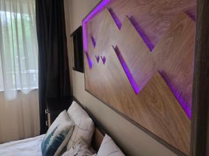 a bedroom with a bed with a purple painting on the wall at Borovets Gardens Studio Raya in Borovets
