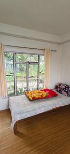 a bed in a room with a large window at The Jhandi Nest in Gorubathān