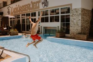 a man jumping in the water in a swimming pool at Kinderhotel Laderhof in Ladis