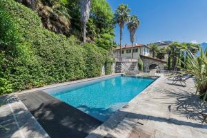 a swimming pool in a yard with trees and a house at Luxury Villa in Tremezzo con piscina in Tremezzo
