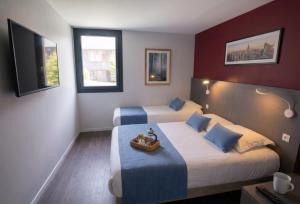 a hotel room with two beds and a television at Brit Hotel Montpellier Euromédecine in Montpellier