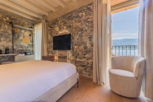 a bedroom with a bed and a chair and a tv at La Corte Del Lario - Contrada Scoscesa in Varenna