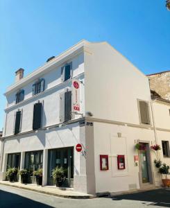 a white building with plants in front of it at Hôtel Restaurant de la Place in Saint-Jean-dʼAngély