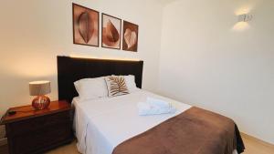 a bedroom with a bed and a nightstand with a white bedspread at Suíte no Centro de Caxambu - Poucos metros do Parque in Caxambu